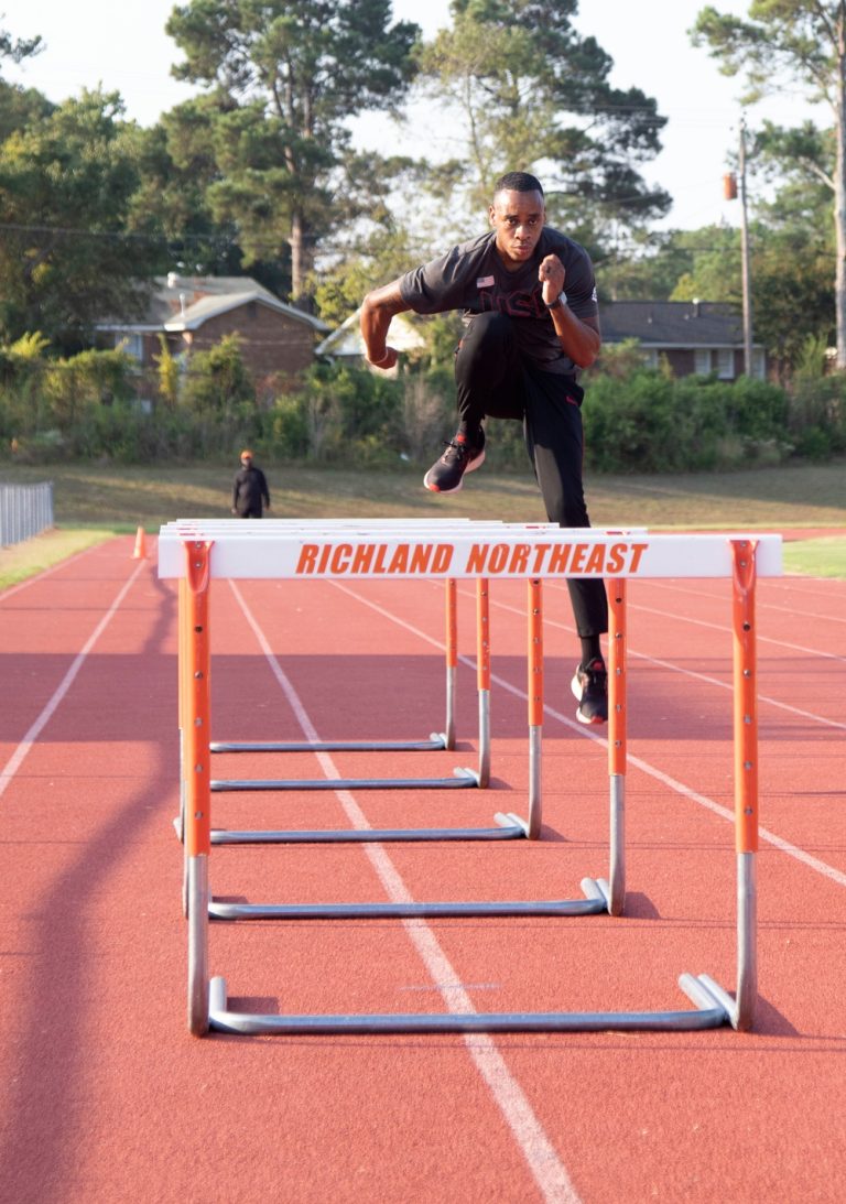 U.S. Army Sgt. Marcus Maxey demonstrates hurdling form during training at Richland Northeast High School for coach Lawrence Terry.