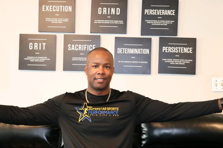 Lawrence Superstar Terry seated in a Superstar Sports Performance shirt beneath motivational coaching words.